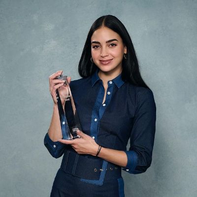 Melissa Barrera is holding the award and smiling in this pic.